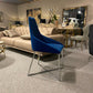 A furniture showroom featuring a sofa, artwork, mirrors, and a blue chair with a metallic frame in the foreground, alongside an elegant set of Home Signature Venice Dining Chair in Blue Colour.